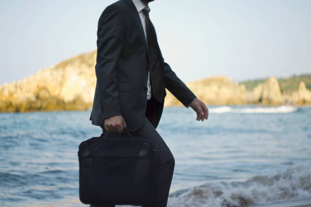 istock Walking businessman with handbag on the beach 869098460