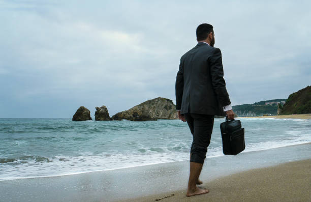 istock Walking businessman with handbag on the beach 869098468