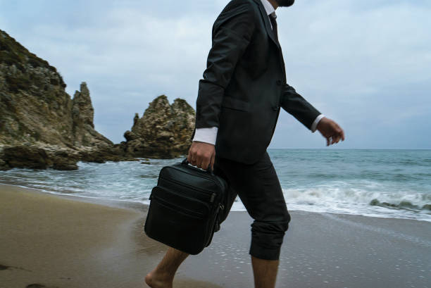 istock Walking businessman with handbag on the beach 869098472