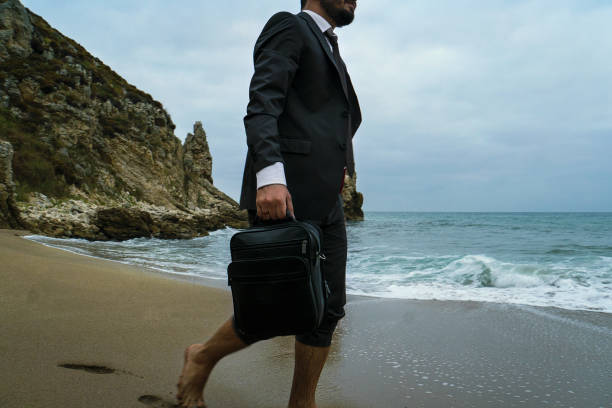 istock Walking businessman with handbag on the beach 869098502