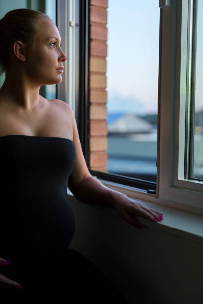 istock Thoughtful pregnant woman looking out the window 869108548