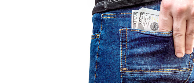 A man puts money in the back pocket of jeans. Isolated on white.