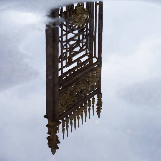 istock Old decorative iron fence reflected in puddle among the blue sky with clouds after rain. Concept dream, paradise 869119598