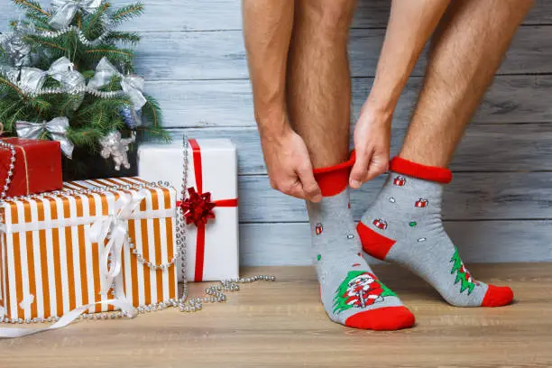 Photo of Closeup image of a man who adjusts his New Year's woolen socks.