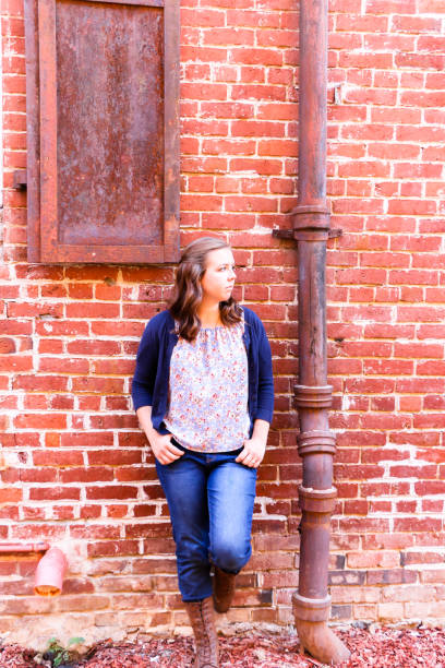 istock Girl Leaning Against Red Brick Wall 869134508