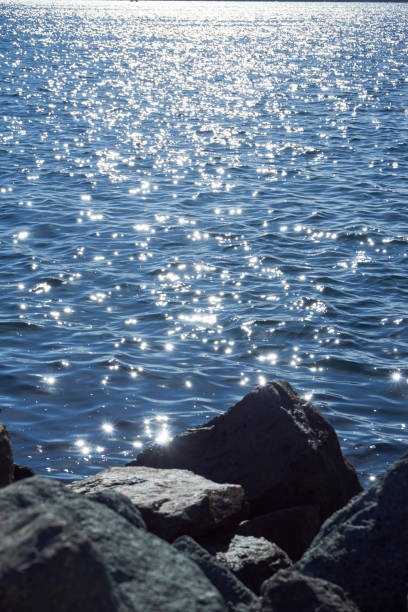sun sparkles dancing on blue water stock photo