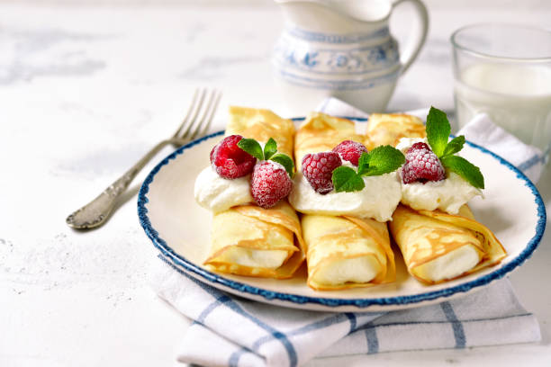 Crepes stuffed with ricotta Crepes stuffed with ricotta on a vintage plate on a light slate,stone or concrete background. crêpe pancake stock pictures, royalty-free photos & images