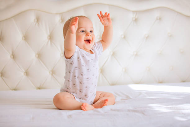 Cute baby boy in white sunny bedroom stock photo