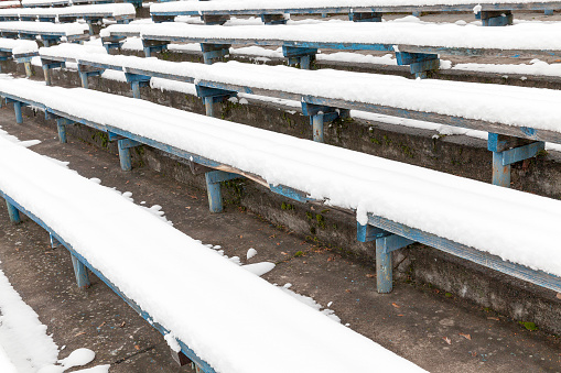 old wooden benches at stadium in the winter season covered with white snow after the snowfall