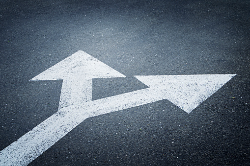 A bi-directional arrow symbol on an asphalt road for the concept of choice