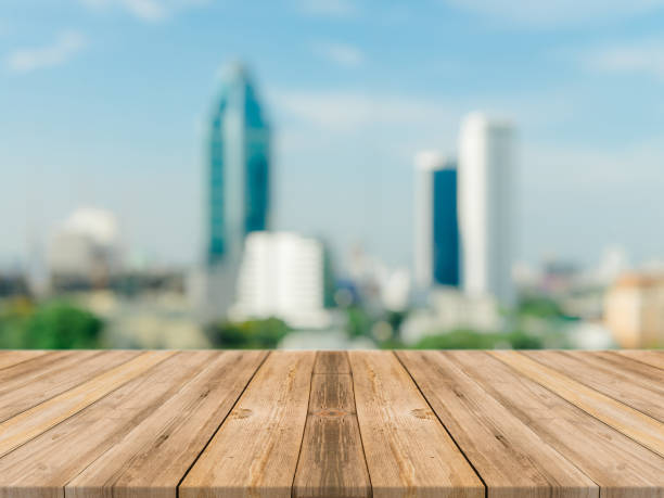 istock Wooden board empty table top blurred background. Perspective brown wood table over blur city building view background - can be used mock up for montage products display or design key visual layout. 869160176