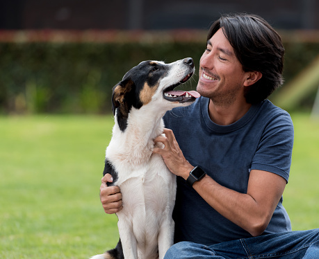 Portrait of a happy Latin American man playing with his dog outdoors â lifestyle concepts