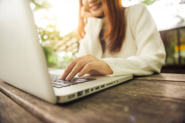 imagen recortada de joven, utilizando la computadora portátil en la cafetería. retrato de mujer asiática trabajando en ordenador portátil, con enfoque en la laptop de cerca. mujer asiática joven sentado en el restaurante ocupado trabajando en ordenador portátil - asian cuisine audio fotografías e imágenes de stock