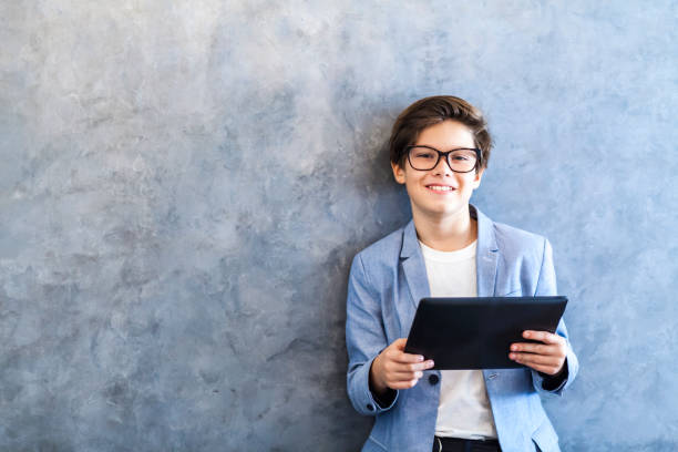 istock Smiling teen boy posing with digital tablet by wall 869171586