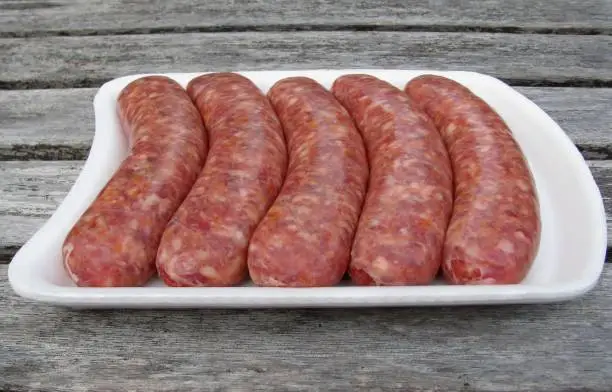 Photo of Fresh raw sausages on white styrofoam tray