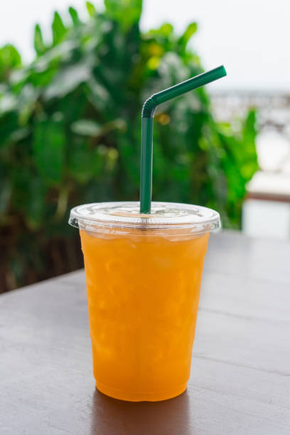 istock Orange juice  in a plastic glass placed on a wooden table. 869192104