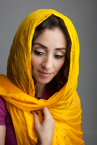 Portrait of a muslim woman wearing a yellow silk headscarf, studio shot