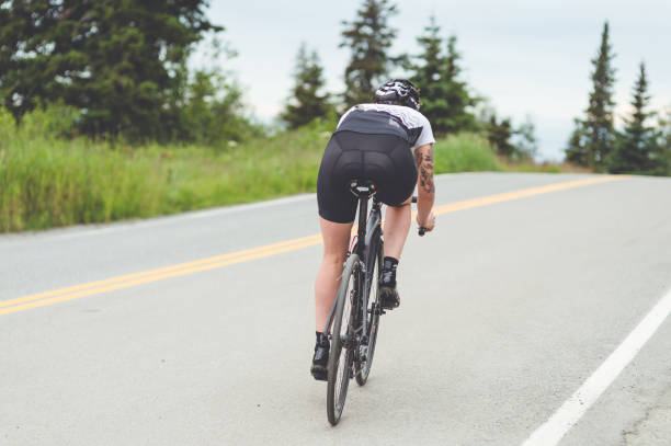 istock Female cyclist rides along a rural highway 869196294