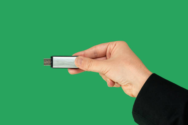 pendrive de metal en mano con fondo verde aislado. vista frontal - usb cable stick usb flash drive pendrive fotografías e imágenes de stock