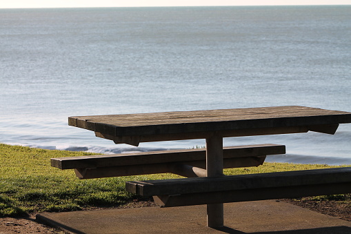 An empty picnic bench in late afternoon sunlight at a New Plymouth beach.