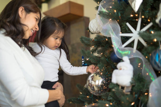 istock Young girl and her mom put decorations on the Christmas tree 869212018