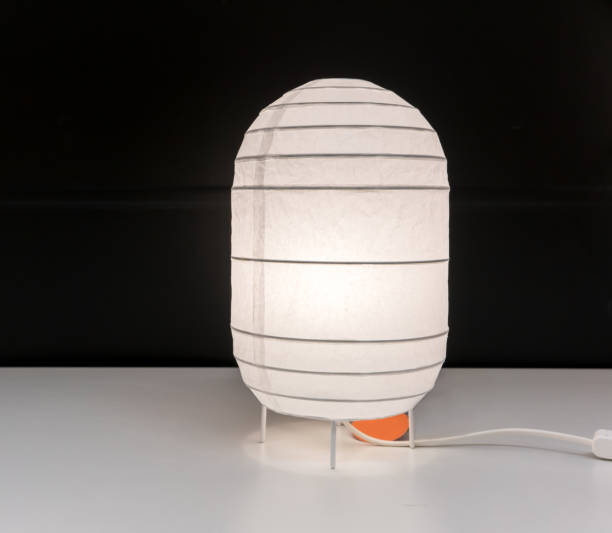 istock White paper lamp with switch on cord isolated on desk against black wall. 869219622