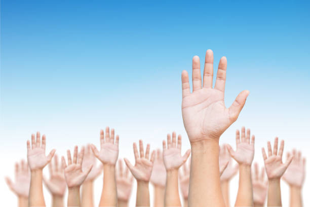 istock Business crowd raising hands high up on blue skies background. 869223038