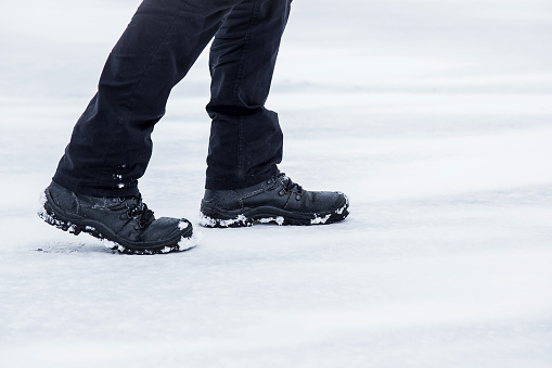 Man walking in winter day. Winter boots on legs. Active lifestyle at nature. Winter concept.