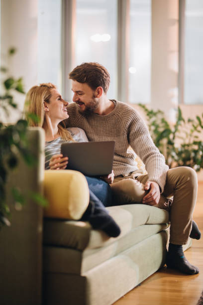 istock Young happy couple communicating while using computer in the living room. 869226684