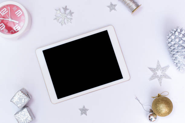 istock Computer laptop mobile display on table with isolated white screen for mockup in Christmas time. Christmas tree, gifts, decorations in background. 869229434