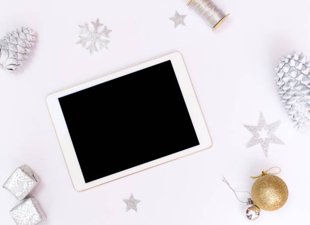 istock Computer laptop mobile display on table with isolated white screen for mockup in Christmas time. Christmas tree, gifts, decorations in background. 869229442