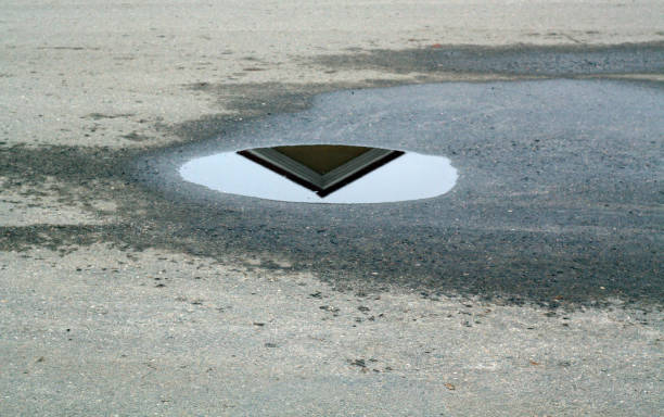 istock Reflection of building roof in puddle on asphalt. 869242296