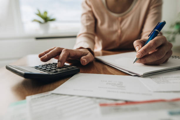 Close up of woman planning home budget and using calculator. Close up of unrecognizable woman using calculator while going through bills and home finances. financial item stock pictures, royalty-free photos & images