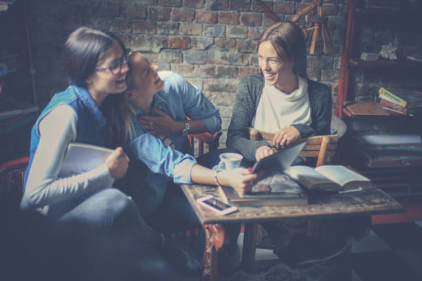 istock Cheerful young students girls sitting in cafe and learning together. 869251362