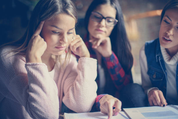 istock Three young students girl at home reading book and working homework. Close up. 869254362