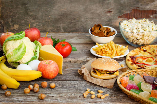 Fastfood and healthy food on old wooden background. Concept choosing correct nutrition or of junk eating. Fastfood and healthy food on old wooden background. Concept choosing correct nutrition or of junk eating. unhealthy eating stock pictures, royalty-free photos & images