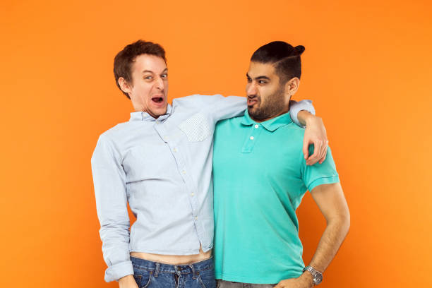Two expressive comic, hugging and grimacing at camera. Two expressive comic, hugging and grimacing at camera. Studio shot blue and green braces stock pictures, royalty-free photos & images
