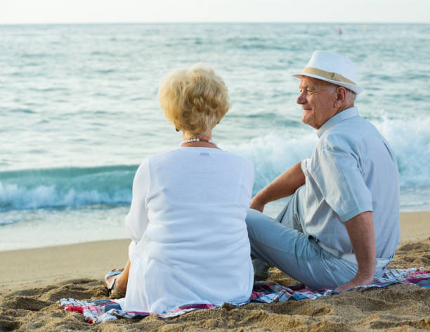 istock Mature man and woman sitting back on towel 869262082