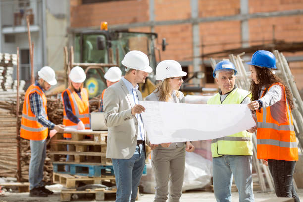 Group Construction workers looking at blueprints on construction site Construction workers talking on site coordination photos stock pictures, royalty-free photos & images