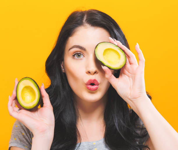istock Happy young woman holding avocado halves 869263032