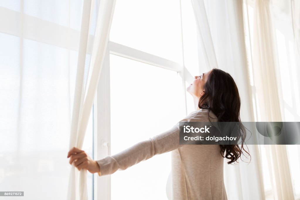 close up of pregnant woman opening window curtains pregnancy, motherhood, people and expectation concept - close up of happy pregnant woman opening window curtains Curtain Stock Photo