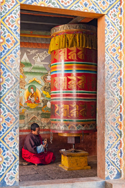 monje orando en una casa de la rueda de oración - bhután - bhutan himalayas wheel vibrant color fotografías e imágenes de stock