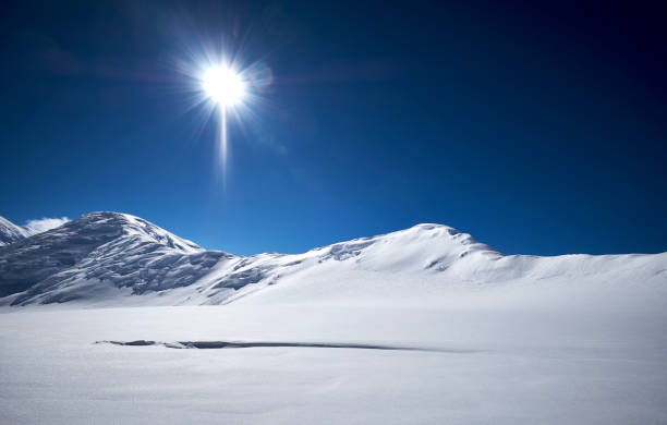 Sunny day on the glacier in the snow, with the mountains in the background.