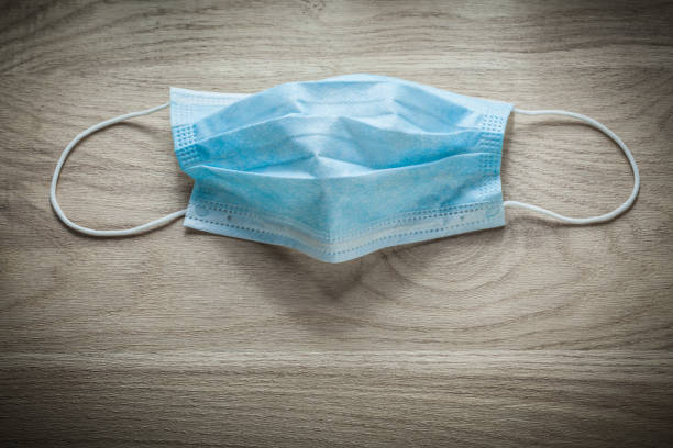 istock Disposable surgical sterile mask on wooden board 869282022