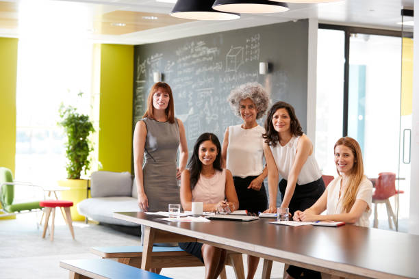 istock Five female colleagues at a work meeting smiling to camera 869282780