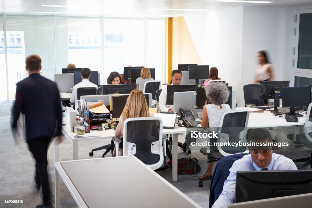 Man walking through a busy open plan office Office Stock Photo