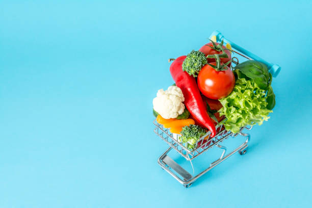 istock Shopping cart with fresh vegetables close-up on blue background 869285922