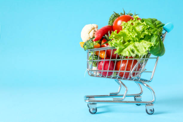 istock Shopping cart with fresh vegetables close-up on blue background 869285940