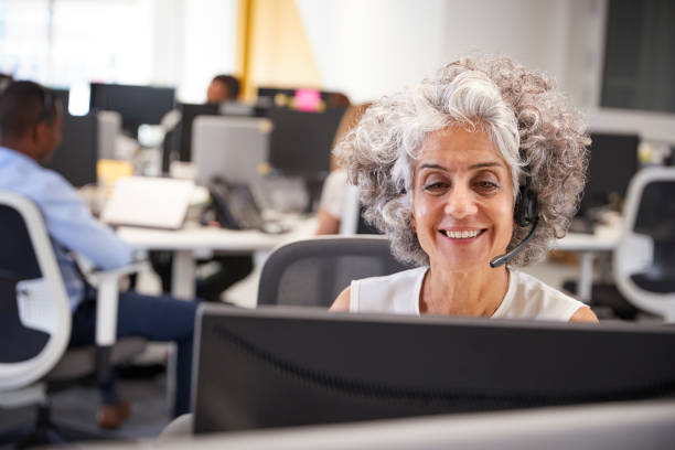 istock Middle aged woman working at computer with headset in office 869285970