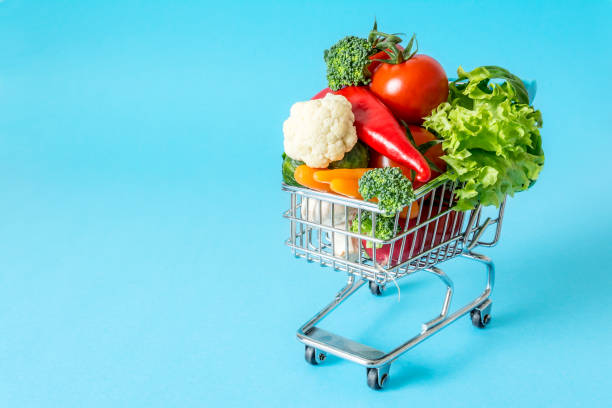 istock Shopping cart with fresh vegetables close-up on blue background 869285988